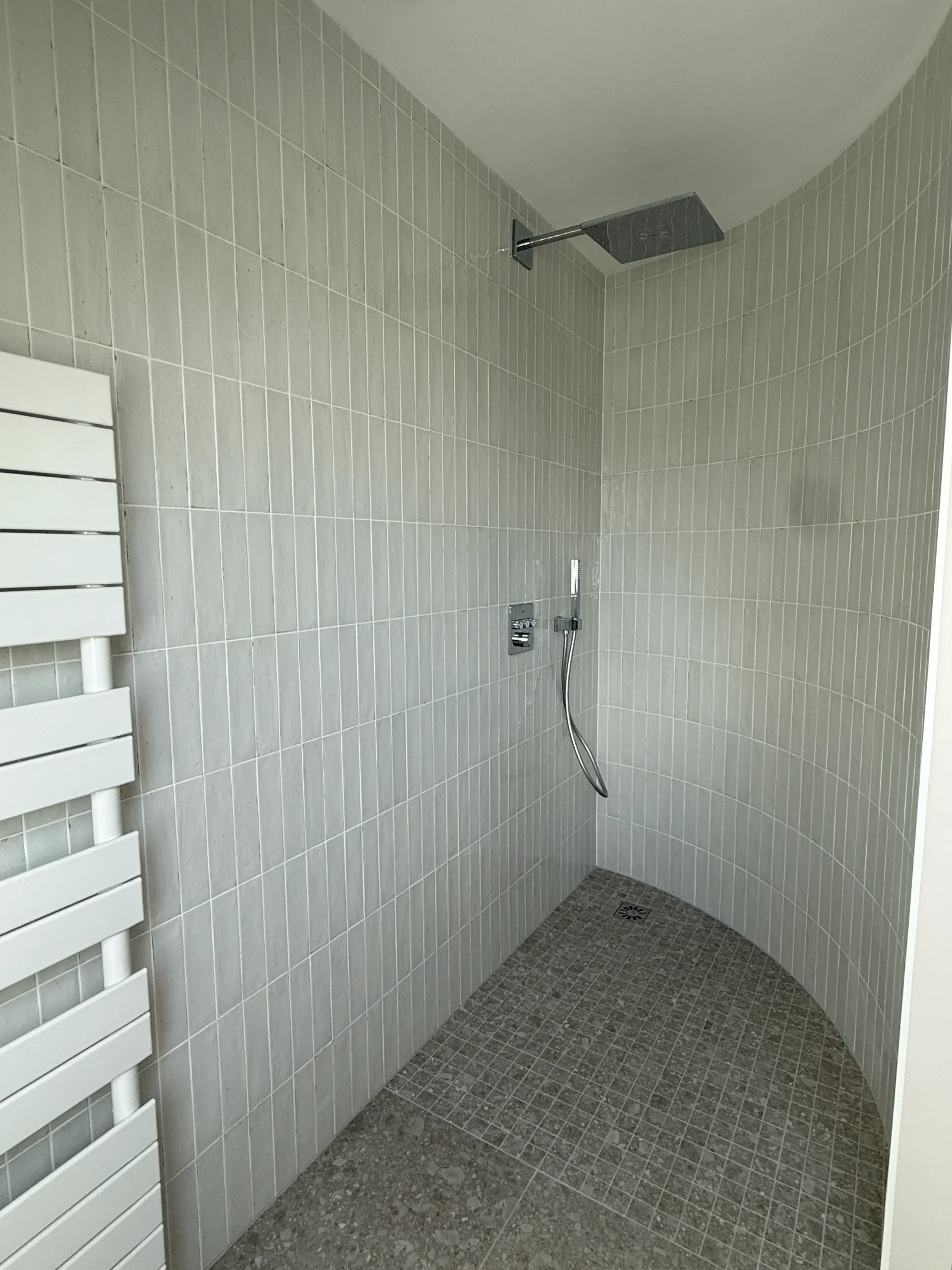Douche à l’italienne carrelée avec pommeau, douchette et évacuation au sol